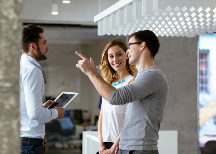 Three business people talking in an open office area
