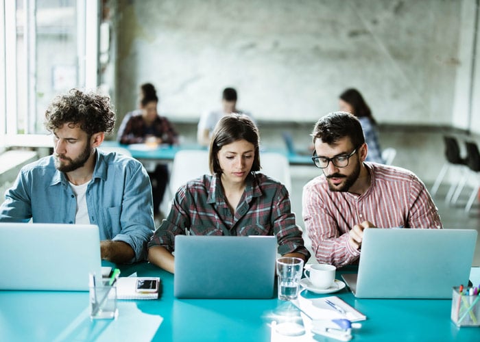 Collaborative Team Working on Laptops in Modern Open Office Workspace