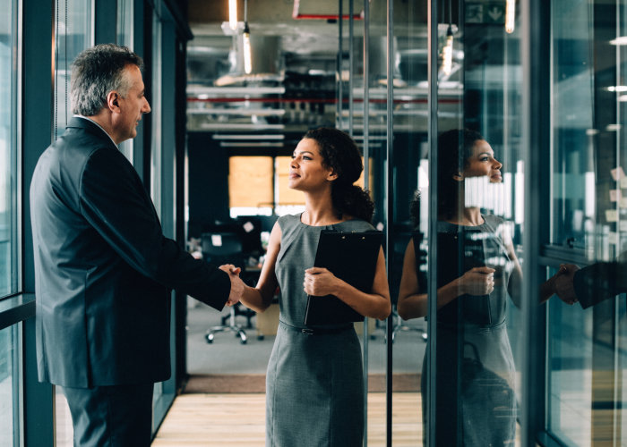 Business people shaking hands in an office hallway