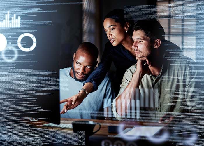 Coworkers looking at data on a large monitor in a dark room