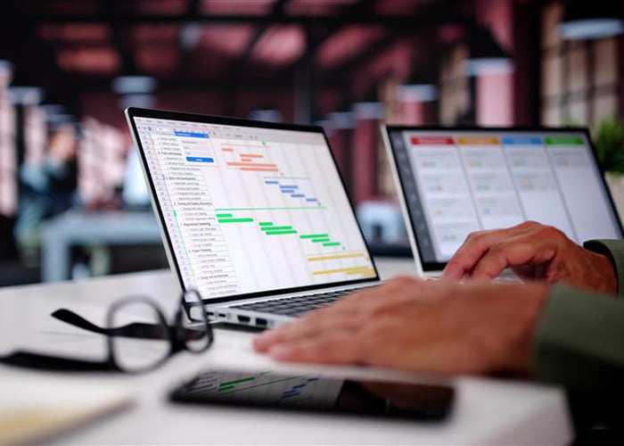 Laptop displaying a project management dashboard with charts and task lists.