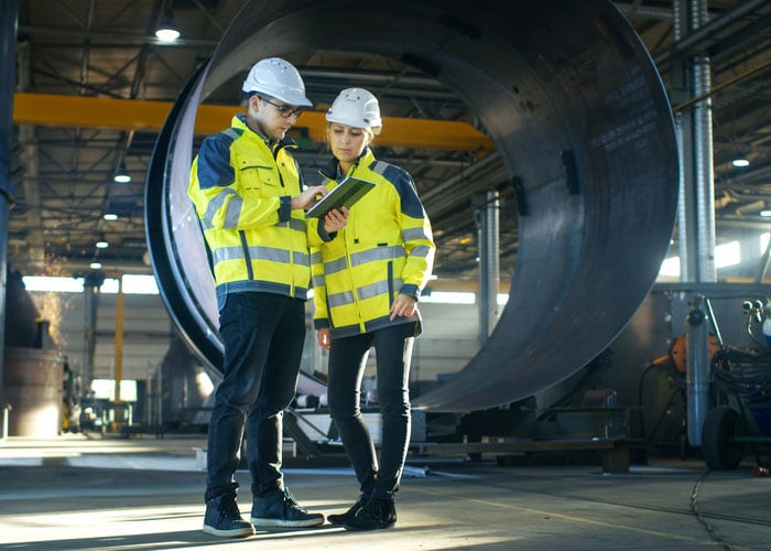 Two Industrial Engineers Reviewing Project Data on Tablet 