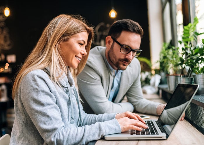 Two Business Professionals Collaborating on Project Work Using Laptop in Office