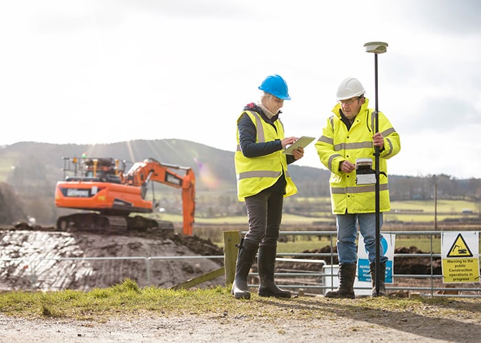 Civil Engineers Conducting Site Survey and Reviewing Project Data at Active Excavation Site