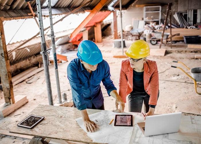 Architect and Construction Manager Reviewing Building Plans and Project Data on Active Renovation Site