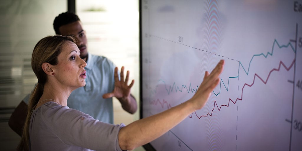 People looking at a price index/earnings graph going upwards and discussing 