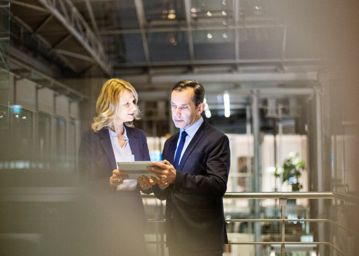 Formal business people talking and looking at a tablet device
