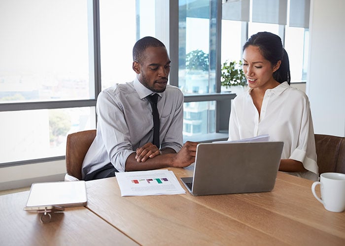 Businesspeople working on laptop in boardroom together
