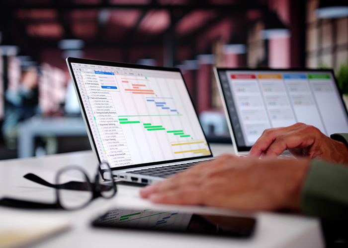 Project Manager Updating Gantt Chart Schedule and Task Timelines on Laptop