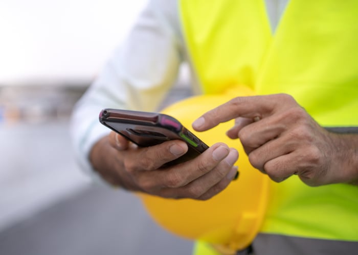 Construction worker typing on a cell phone
