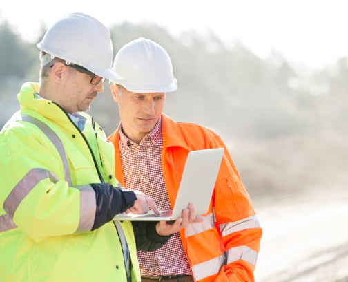 Two construction engineers monitoring a project in the field using a laptop