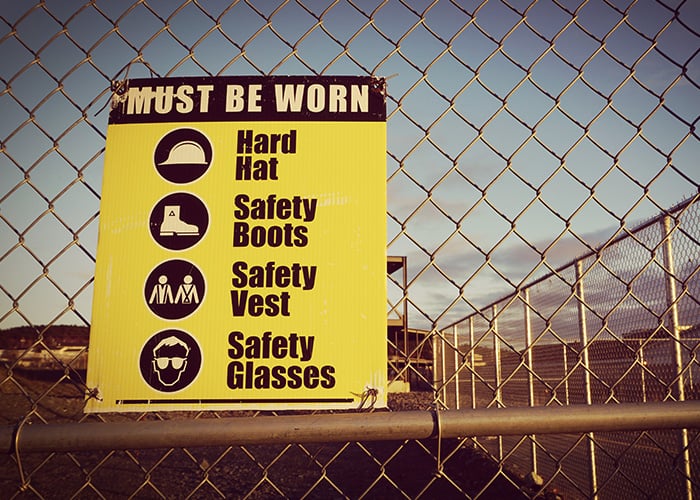 Construction Site Safety Compliance Sign Displaying Required Personal Protective Equipment on Job Site Fence