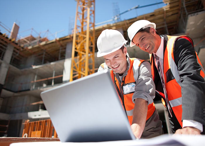Construction workers using laptop on construction site