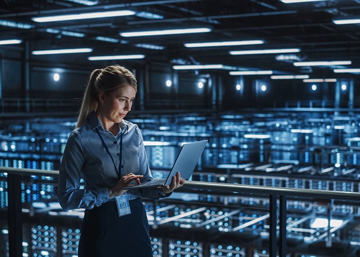 Female IT specialist using a laptop in a data center