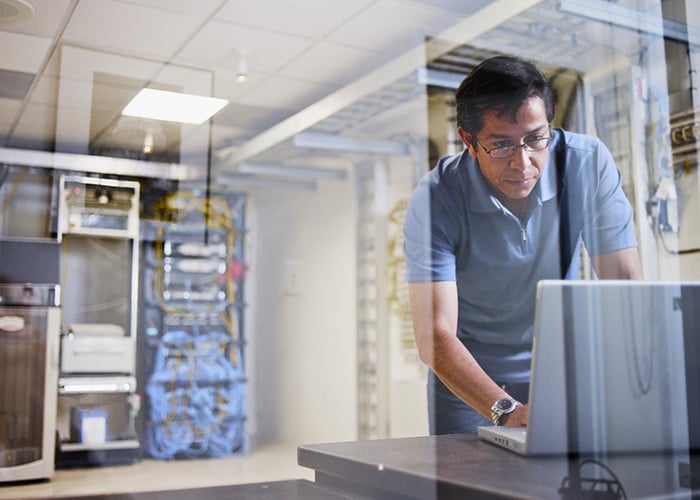 Engineer using a laptop behind a glass