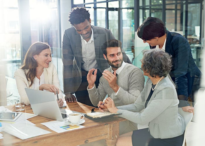 Business team collaborating in an office meeting around a laptop