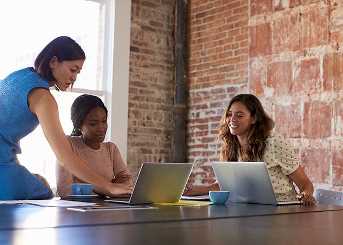 Female Business Team Collaborating on Laptops in Modern Creative Office