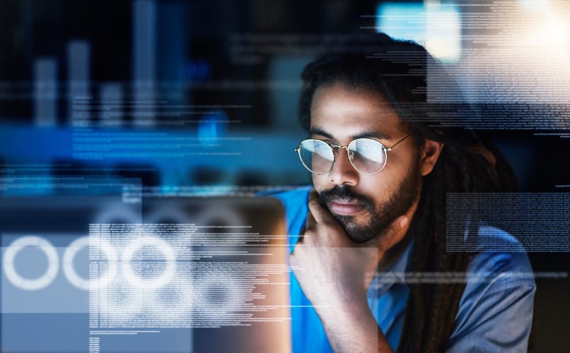 Software Developer Analyzing Code and Digital Data Streams on Computer Screen