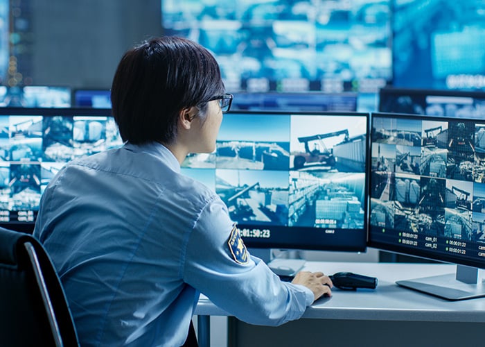 Security officer monitoring multiple screens in a control room