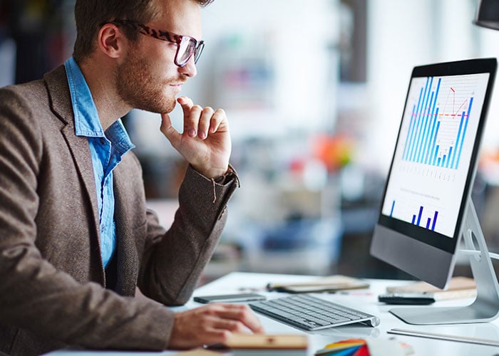 Male office worker looking at a computer screen with data