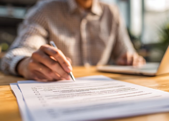 Professional reviewing and completing a project costing document at a desk
