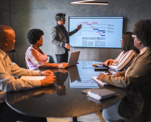 Project Manager Presenting Gantt Chart Schedule and Execution Plan to Executive Team in Boardroom