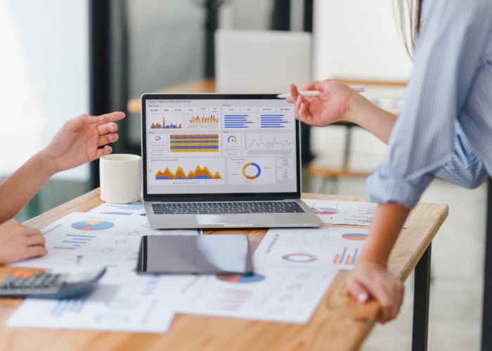 Business people discussing data looking at charts on a laptop