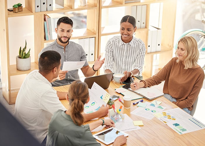 Diverse Business Team Collaborating on Project Reports and Deliverables in Office Meeting