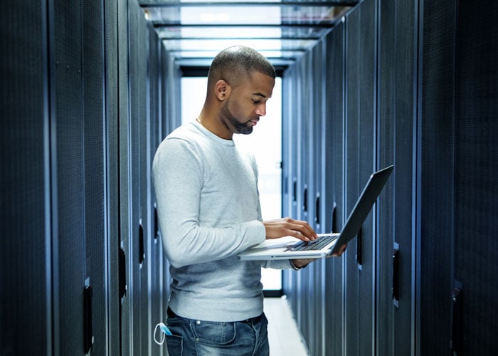 IT Technician Managing Server Infrastructure and Network Operations with Laptop in Data Center