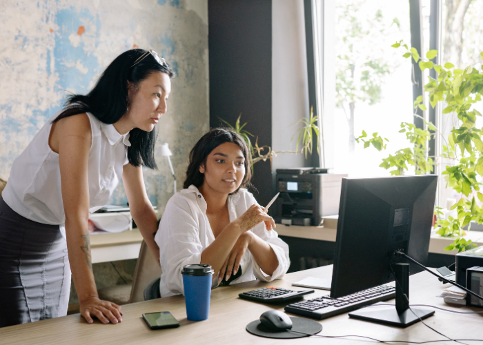 Two female business people looking at a computer monitor