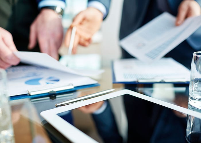 Business Executives Reviewing Financial Reports and Charts with Tablet in Corporate Meeting