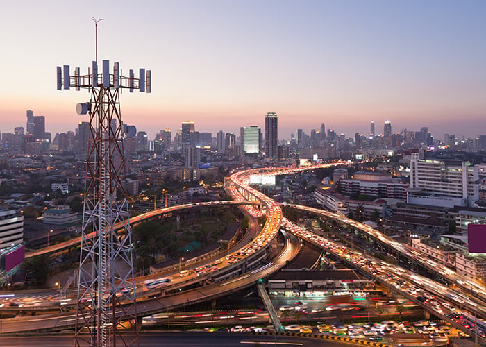 Telecommunication tower with 5G cellular network antenna on city background