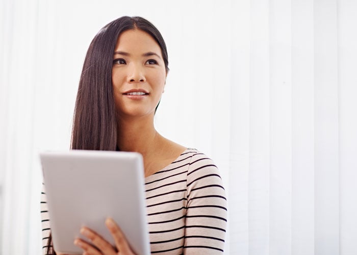 Woman using a tablet while looking to the side.