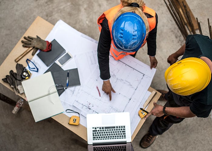 Two Architects examining the blueprints on construction site