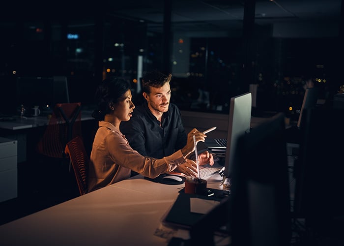 Two people are looking at a monitor and discussing a project.