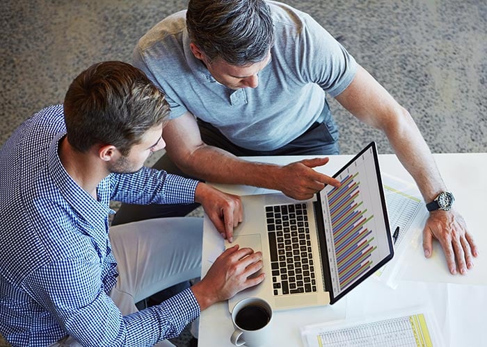 Two colleagues using a laptop in a meeting at the office