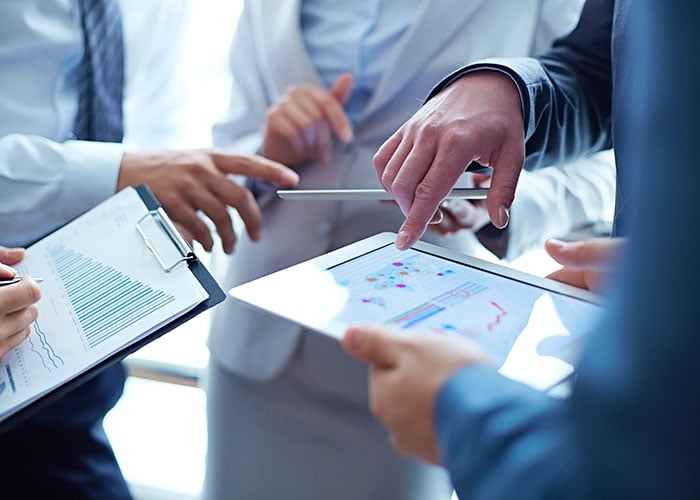 Business Executives Reviewing Financial Performance Charts and Analytics on Tablet in Corporate Meeting