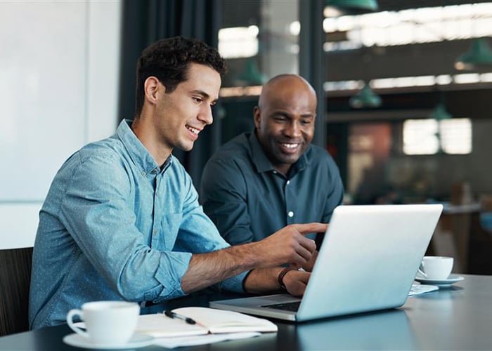 Two colleagues reviewing timesheet data together on a laptop