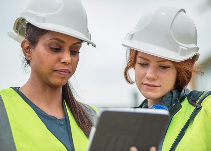 Construction team reviewing plans on tablet at job site