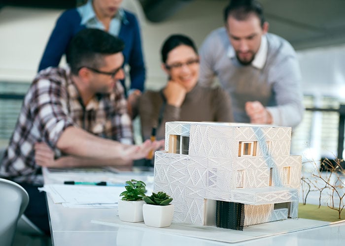Architecture Team Collaborating on Building Scale Model and Design Plans in Studio