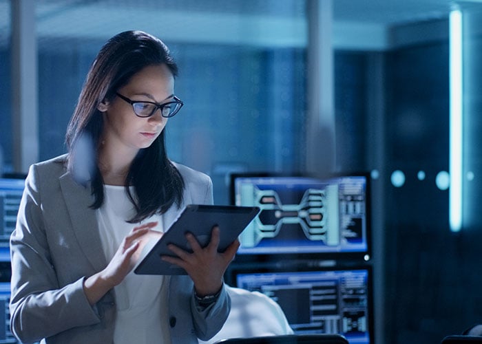 Young woman wearing glasses using a tablet in a system control center.