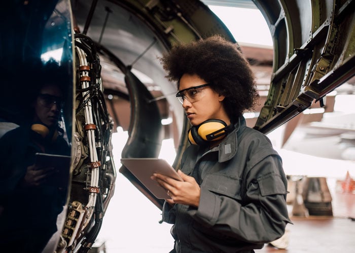 Young airplane engine mechanic using a digital tablet