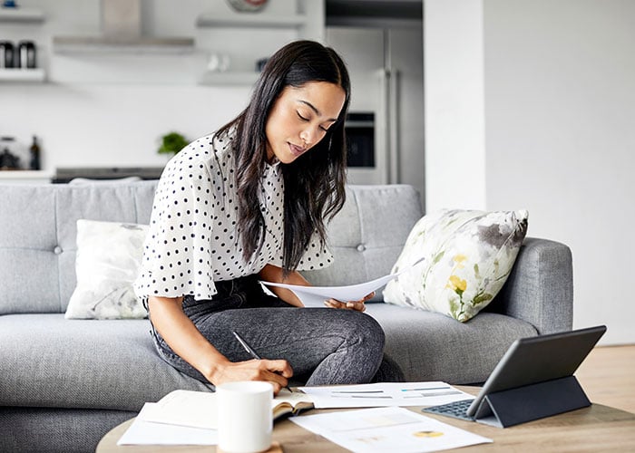 Young woman analyzing bills while writing in a diary
